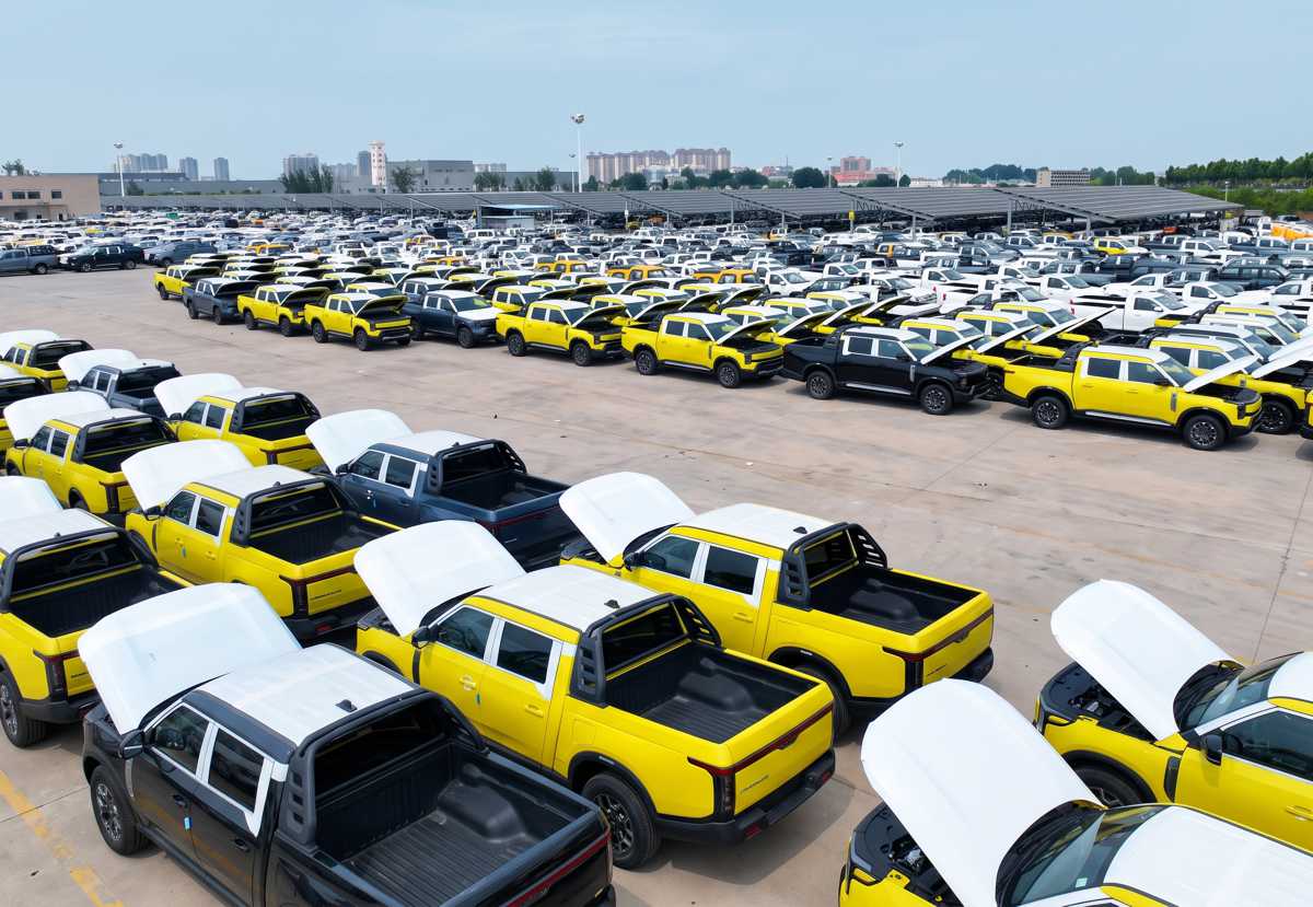 Vista aérea de un patio de almacenamiento en China con cientos de pick-ups Nissan Frontier Pro con capós abiertos durante las inspecciones previas al despacho marítimo.