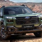 Vista frontal de tres cuartos de la nueva Subaru Outback 2026 en color verde, exhibiendo su agresivo diseño frontal de SUV sobre un terreno rocoso.