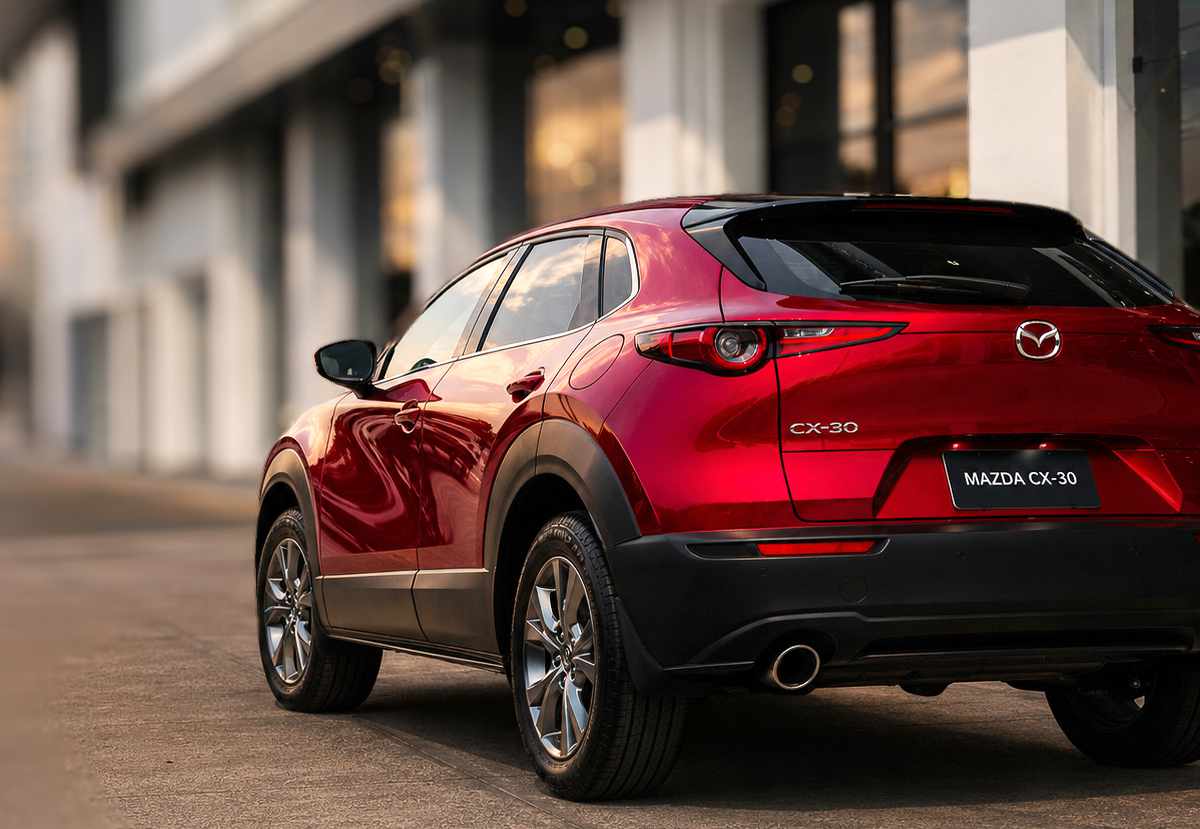 Diseño posterior y pasos de rueda robustos de la Mazda CX-30 híbrida color rojo, lista para realizar un test drive en la ciudad de Bogotá.