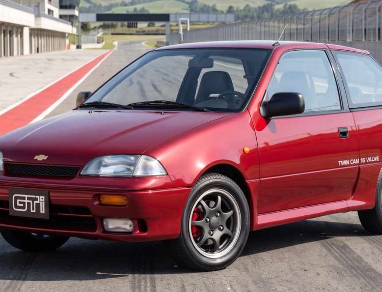 Vista frontal de tres cuartos del clásico Chevrolet Swift GTi color rojo estacionado en una pista de carreras, destacando su diseño deportivo, exploradoras y rines originales.