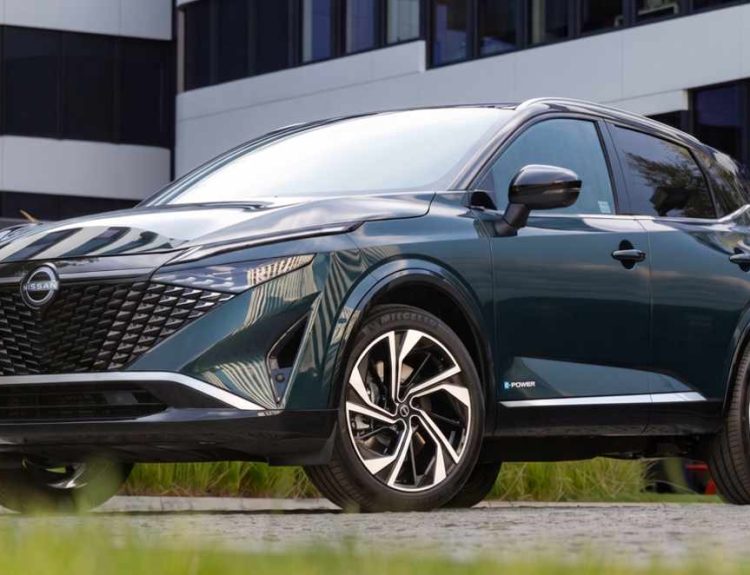Vista frontal de tres cuartos de la Nissan Qashqai e-Power en color verde oscuro, destacando su renovada parrilla ancha y diseño híbrido aerodinámico.