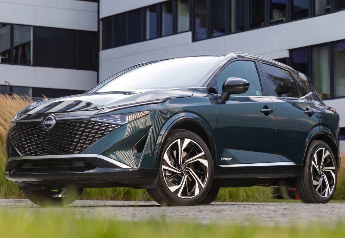 Vista frontal de tres cuartos de la Nissan Qashqai e-Power en color verde oscuro, destacando su renovada parrilla ancha y diseño híbrido aerodinámico.