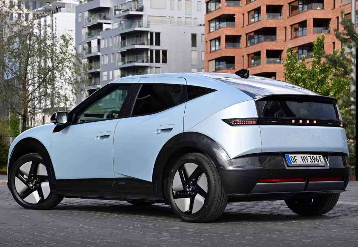 Diseño posterior del Hyundai Ioniq 3 Azul Hielo, resaltando su marcada caída de techo estilo Veloster, el spoiler integrado negro y la firma lumínica trasera LED.
