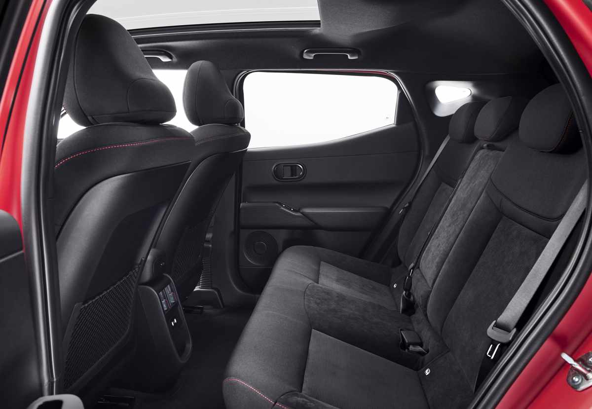 Vista de las plazas traseras del Hyundai Ioniq 3, detallando el espacio para pasajeros, la tapicería oscura en ante con costuras rojas y el amplio techo panorámico.