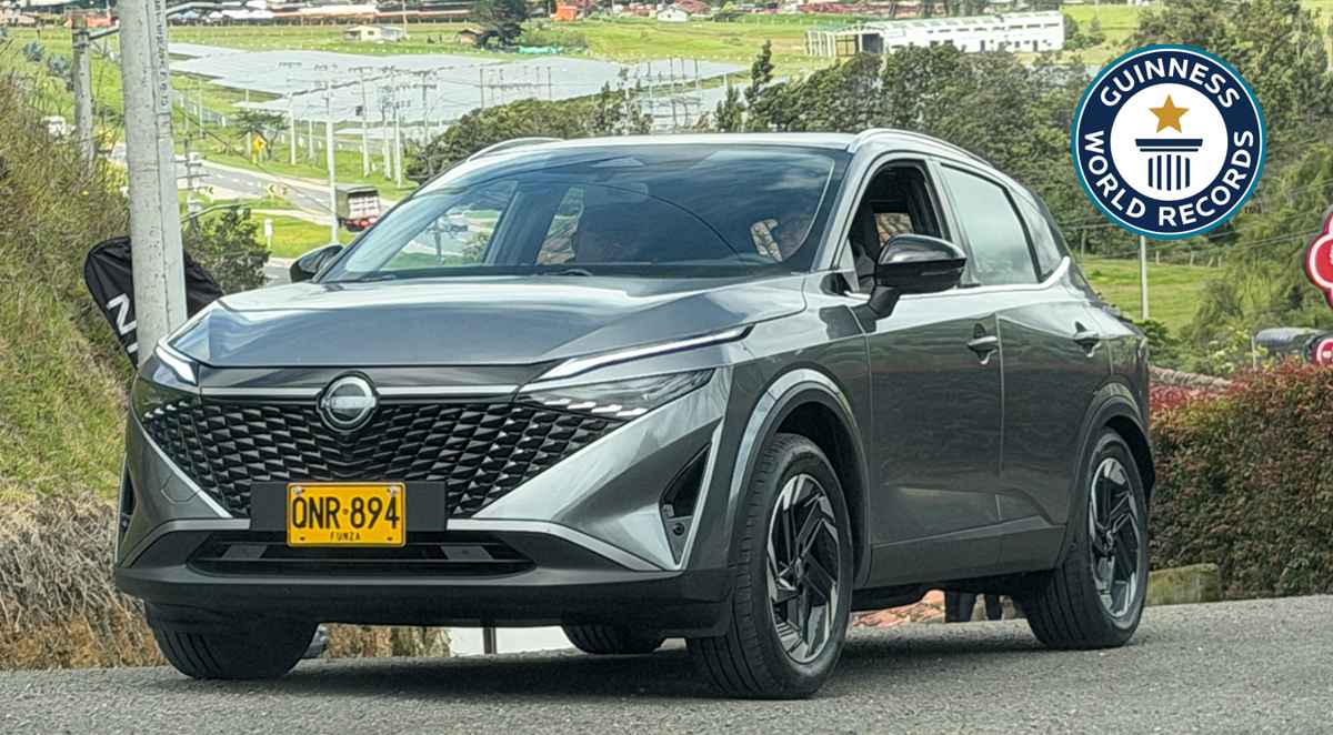 Nissan Qashqai e-Power color gris en movimiento por una carretera de Colombia, acompañada del sello oficial de Guinness World Records por su autonomía.