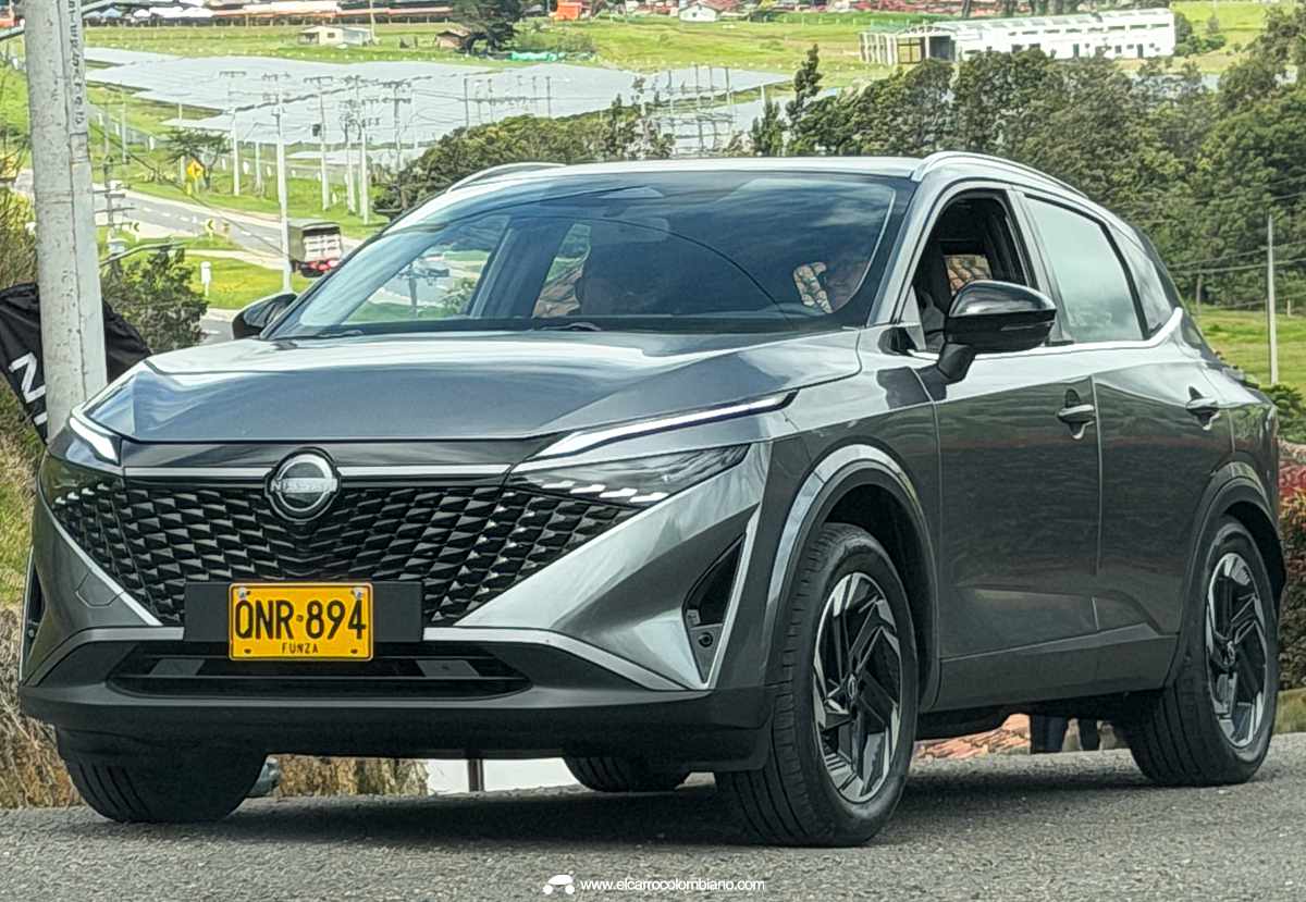 Nissan Qashqai e-Power color gris en movimiento por una carretera de Colombia, acompañada del sello oficial de Guinness World Records por su autonomía.