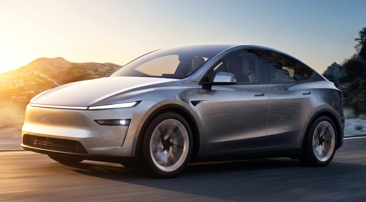 Vehículo eléctrico Tesla Model Y color plata en movimiento por una carretera al atardecer, destacando como el carro más vendido de Colombia en 2026.