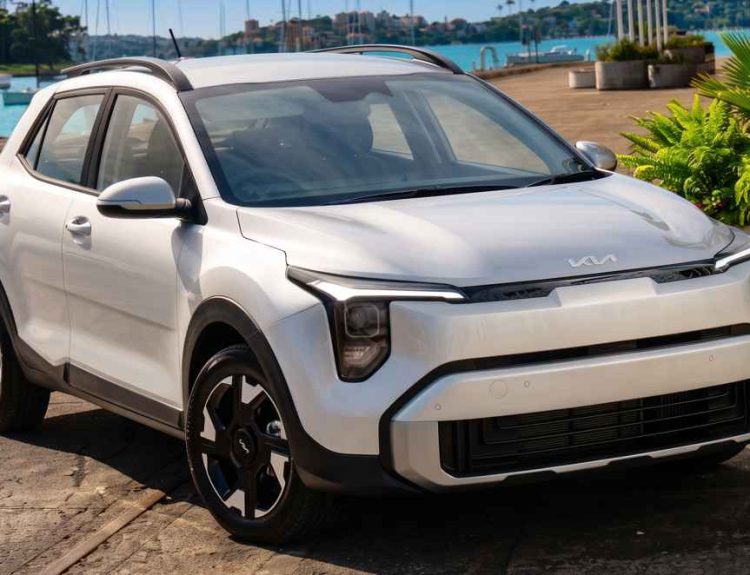 Camioneta híbrida Kia Stonic color blanco estacionada cerca a un muelle soleado, destacando como el vehículo con mayor crecimiento en ventas durante julio de 2026 en Colombia.