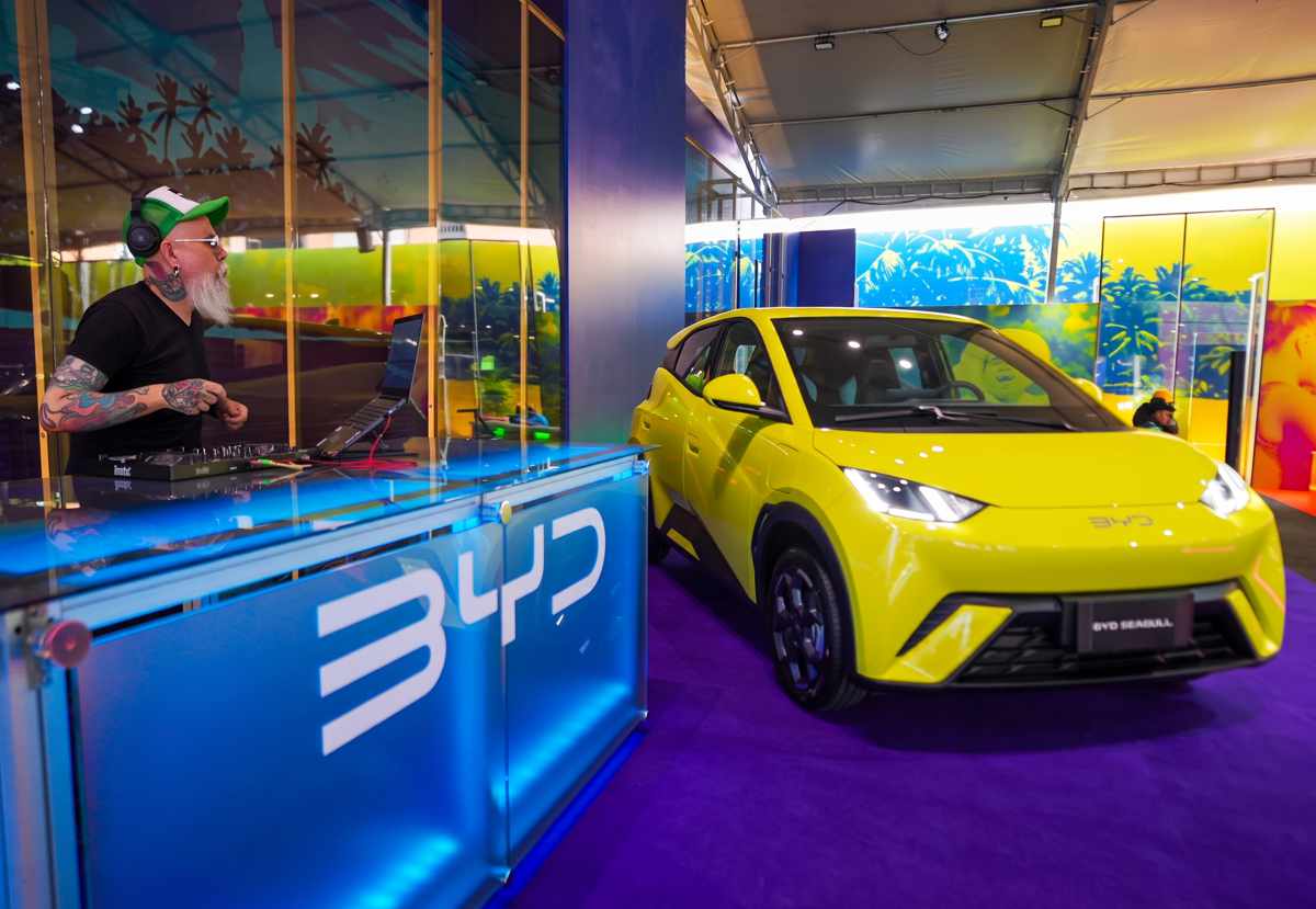 Carro compacto eléctrico BYD Seagull de color amarillo exhibido junto a un DJ tocando música en vivo dentro de las instalaciones del BYD Fest 2026.