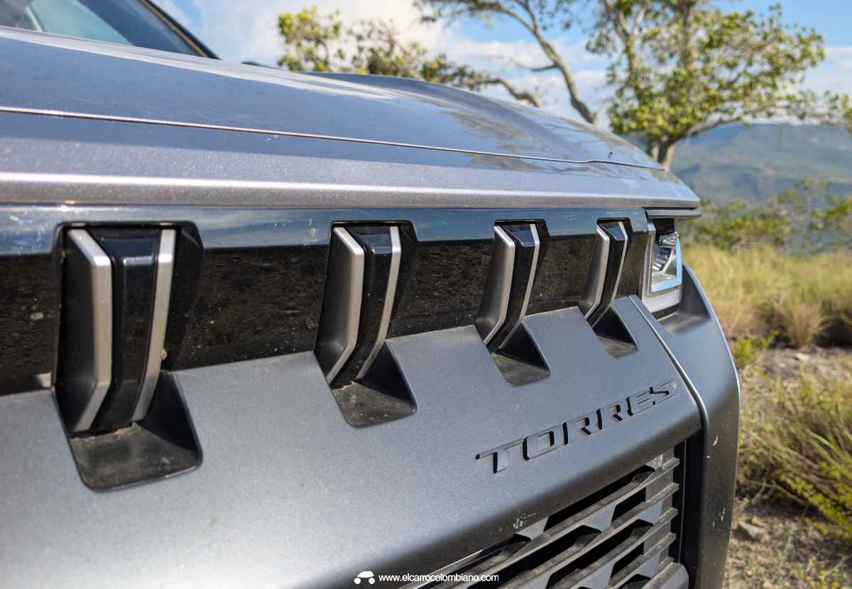 Detalle cercano de la parrilla frontal de la KGM Torres Hybrid, mostrando sus prominentes ranuras verticales plateadas y la tipografía con el nombre del modelo.