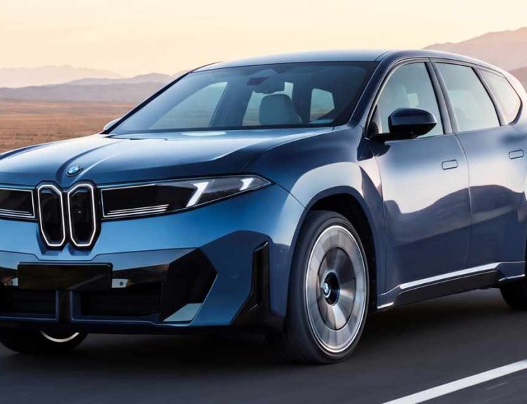 Vista frontal en movimiento de la nueva SUV BMW iX3 eléctrica color azul, destacando su renovada parrilla iluminada y diseño aerodinámico sobre una carretera despejada.