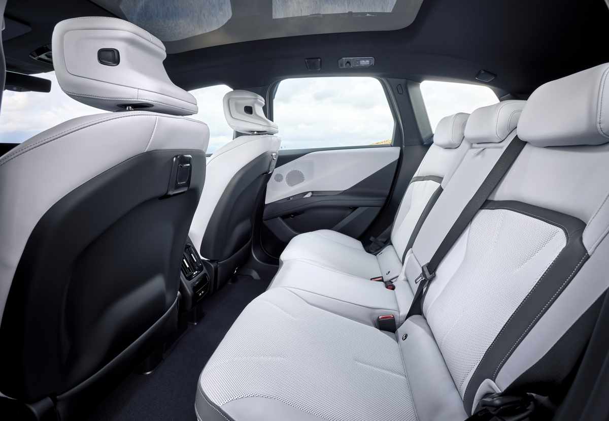 Amplio y refinado espacio en la segunda fila de asientos de la BMW iX3, exhibiendo la lujosa tapicería de cuero sintético Veganza en color blanco perforado.