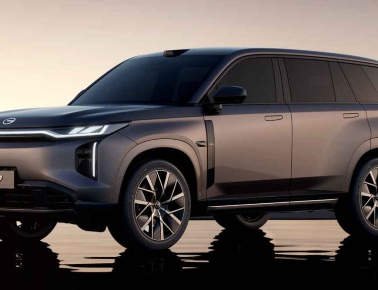 Vista frontal de tres cuartos de la SUV híbrida enchufable GAC S7 color gris oscuro, reflejada sobre una superficie de agua al atardecer, destacando sus luces diurnas LED.