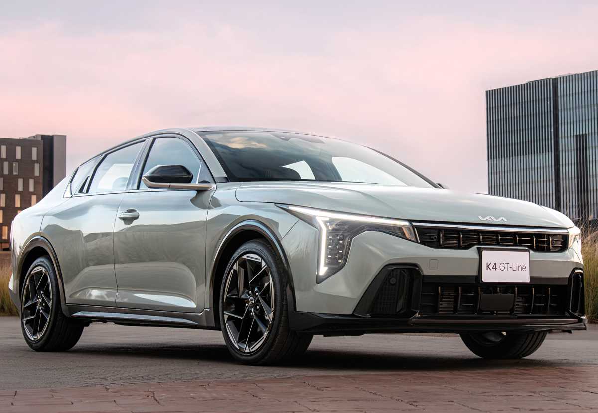 Vista frontal de tres cuartos del Kia K4 Turbo 2027 estacionado al atardecer, exhibiendo su parrilla 'Tiger Face' ensanchada y los ductos decorativos del bumper GT-Line.