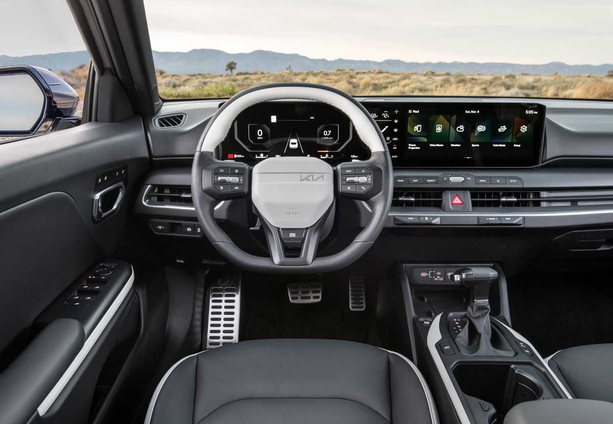 Puesto de conducción tecnológico del Kia K4 Turbo, mostrando el volante multifunción, el panel curvo con doble pantalla de 12,3 pulgadas y la tapicería de cuero bitono.