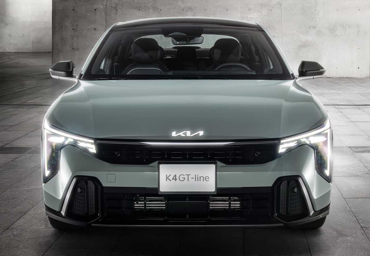 Acercamiento frontal simétrico del Kia K4 GT-Line 2027, detallando el emblema de la marca sobre el capó y la agresiva firma lumínica LED de sus proyectores.