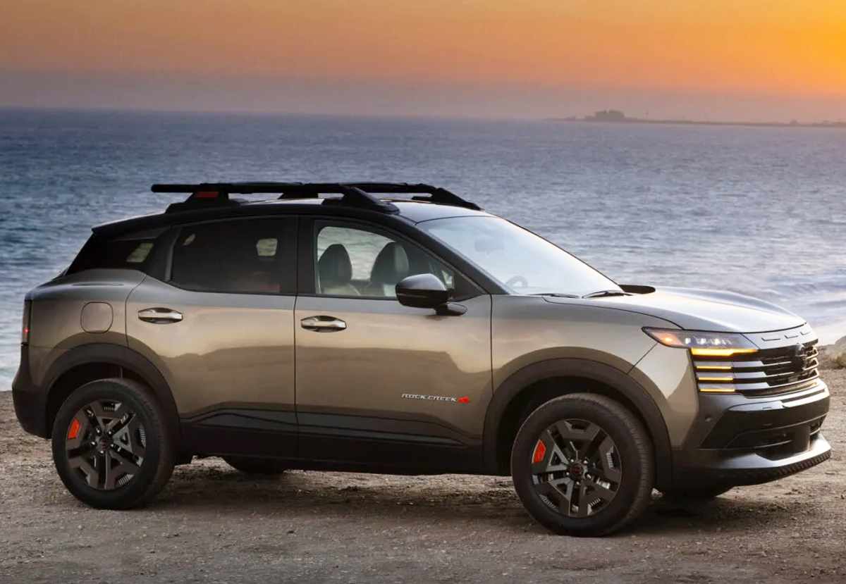 Vista lateral dinámica de la Nissan Kicks Rock Creek 2027 junto al mar al atardecer, mostrando sus rines negros de 17 pulgadas, llantas todoterreno y altura elevada.