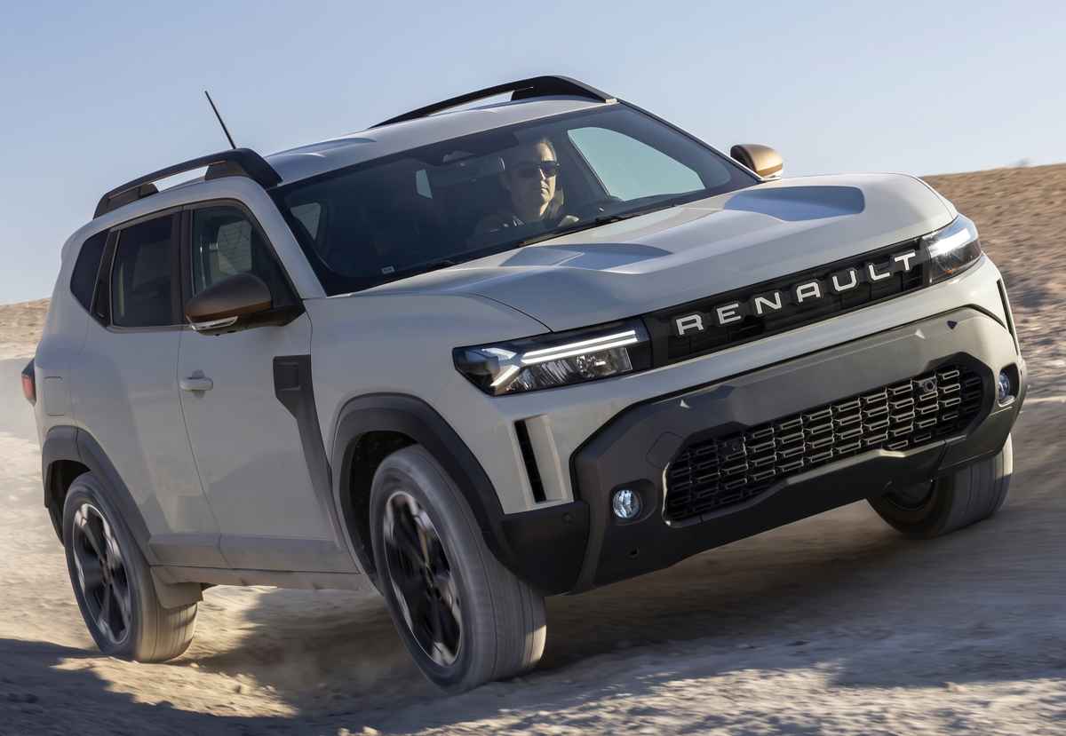 Toma dinámica de tres cuartos de la Renault Duster híbrida 4x4 sorteando un terreno arenoso, exhibiendo los rines bitono de 18 pulgadas diseño 'Extreme' y los robustos protectores del bumper.