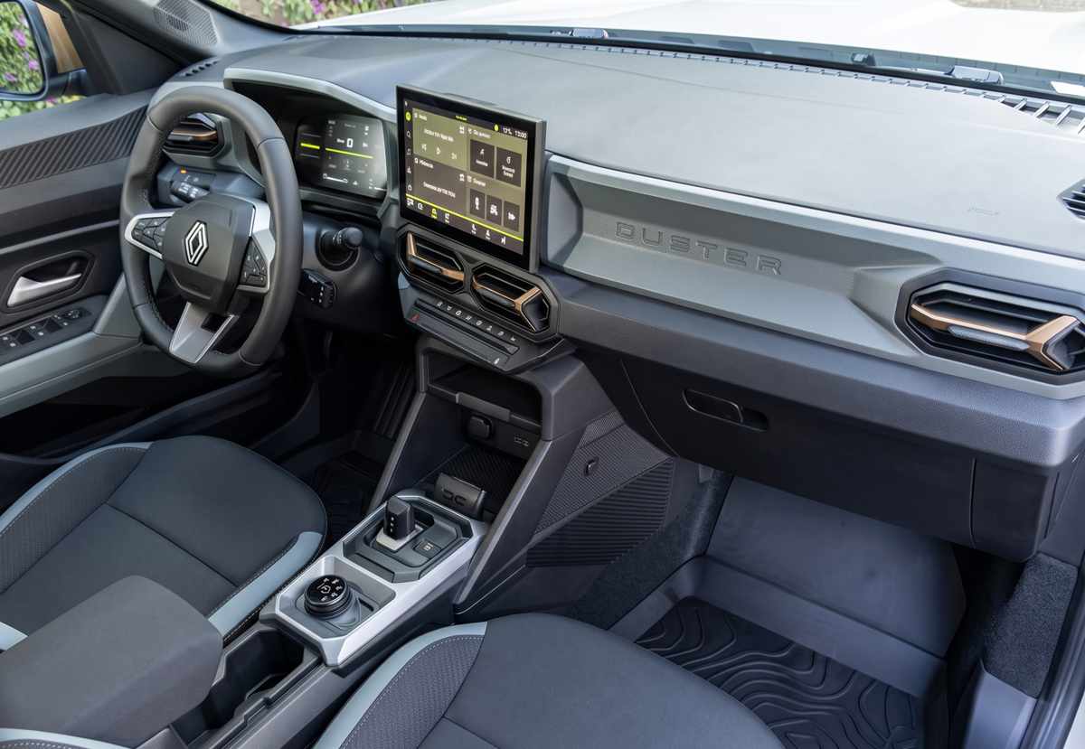 Interior moderno y tecnológico de la Renault Duster automática E-Tech, mostrando el nuevo selector de cambios tipo 'joystick', la pantalla táctil flotante de 10,1 pulgadas y el emblema Duster en el tablero del pasajero.
