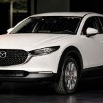 Vista frontal de tres cuartos de una Mazda CX-30 color blanco exhibida en el concesionario Madiautos, modelo que lidera los beneficios para estrenar carros Mazda en Colombia.