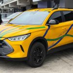 Vista frontal de tres cuartos de la inédita pick-up BYD Mako en color amarillo, exhibida sin camuflaje en los pits de Interlagos, resaltando su amplia parrilla hexagonal.