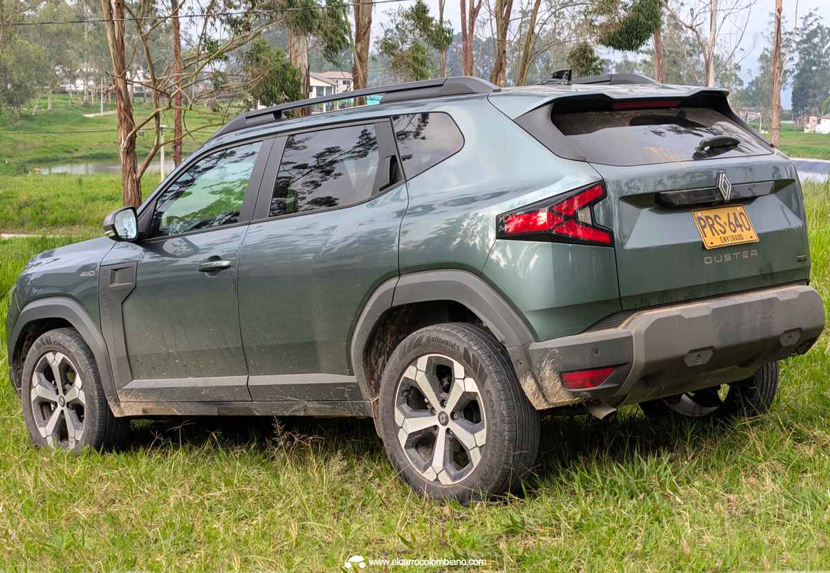 Vista posterior de tres cuartos de la Renault Duster E-Tech 4x4 sobre zona verde, exhibiendo sus luces traseras en forma de Y, spoiler y amplio baúl.