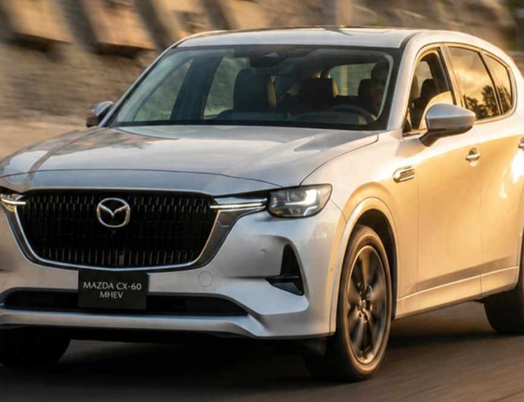 Plano frontal en movimiento de la Mazda CX-60 Híbrida Enchufable color plata, transitando por carretera al atardecer, destacando su imponente diseño Kodo.