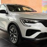 Vista frontal de tres cuartos de la SUV coupé Renault Arkana Evolution color blanco, exhibida sobre una plataforma texturizada durante su presentación en Colombia.