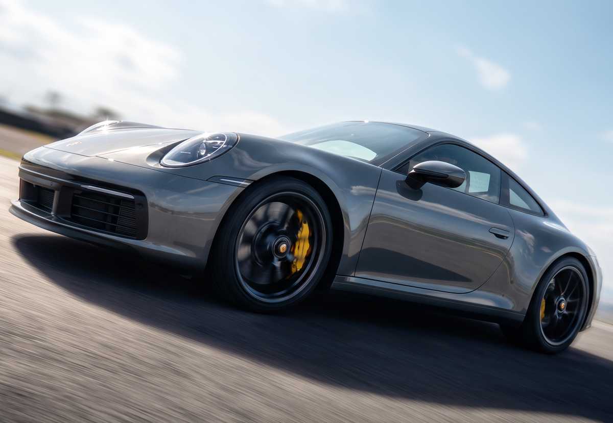 Plano de tres cuartos en movimiento de un Porsche 911 Turbo S color gris oscuro rodando a alta velocidad en pista, ilustrando el destacado crecimiento del 121,4% de la marca en el segmento Premium de Colombia.