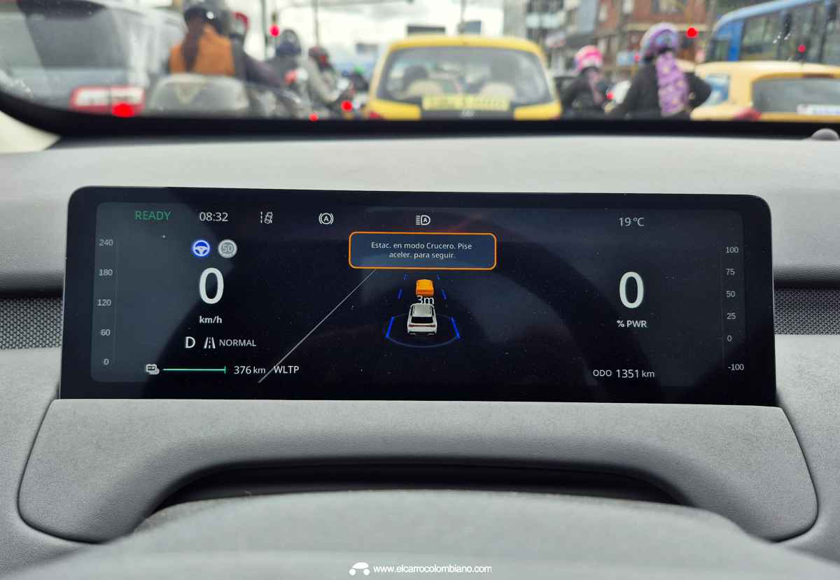 Plano detalle del panel de instrumentos digital de 10,17 pulgadas de la Changan Nevo Q05 durante el manejo en Bogotá, mostrando los gráficos del control crucero adaptativo y la autonomía.