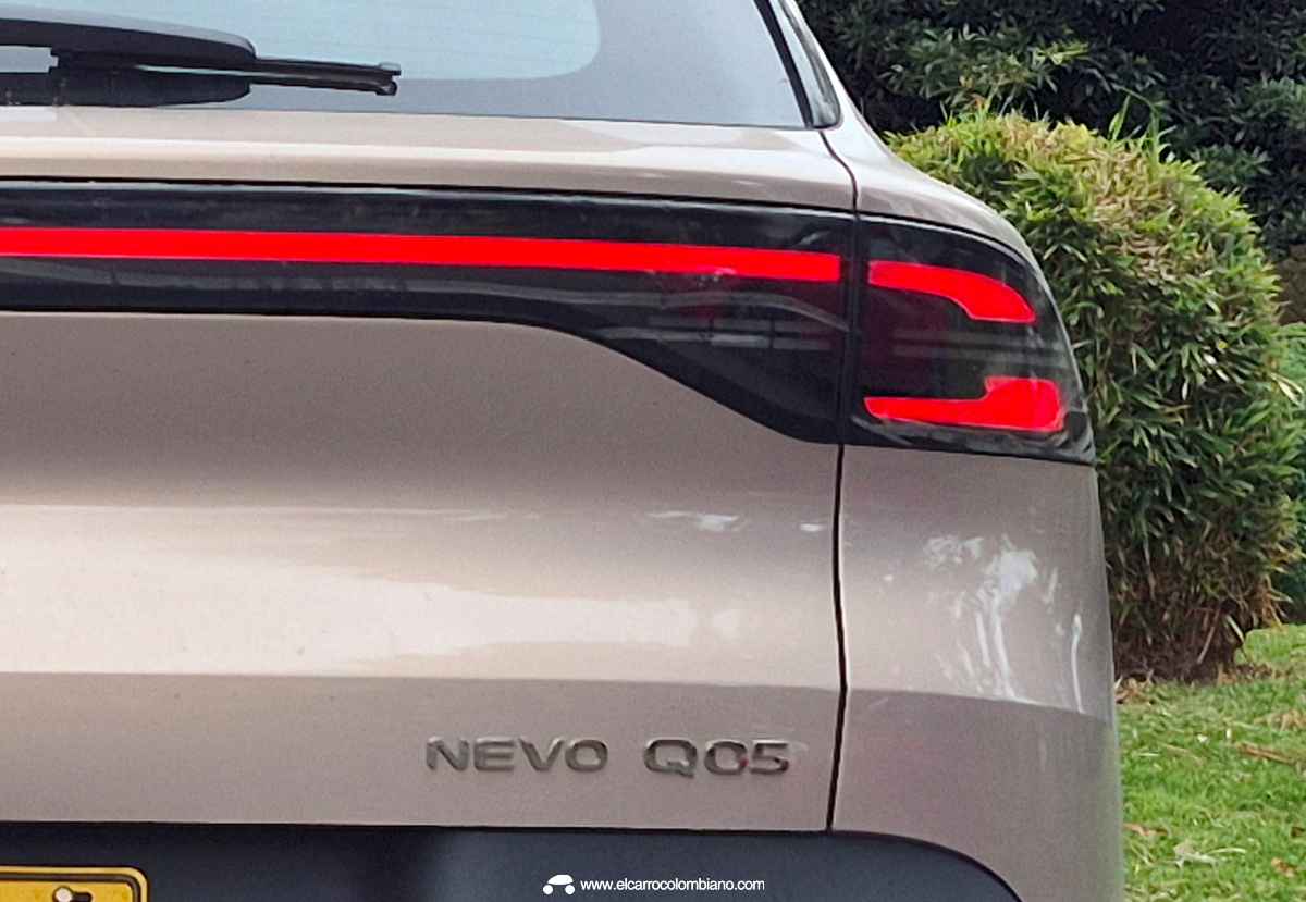 Plano detalle de la zona posterior de la Changan Nevo Q05 Ultra color Magenta Metálico, exhibiendo el diseño continuo de sus luces traseras LED encendidas y el emblema cromado del modelo.
