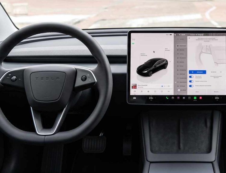 Plano general del interior de un Tesla sin pasajeros, enfocándose en el volante y la pantalla central táctil encendida desde donde se gestiona la Conectividad Premium.