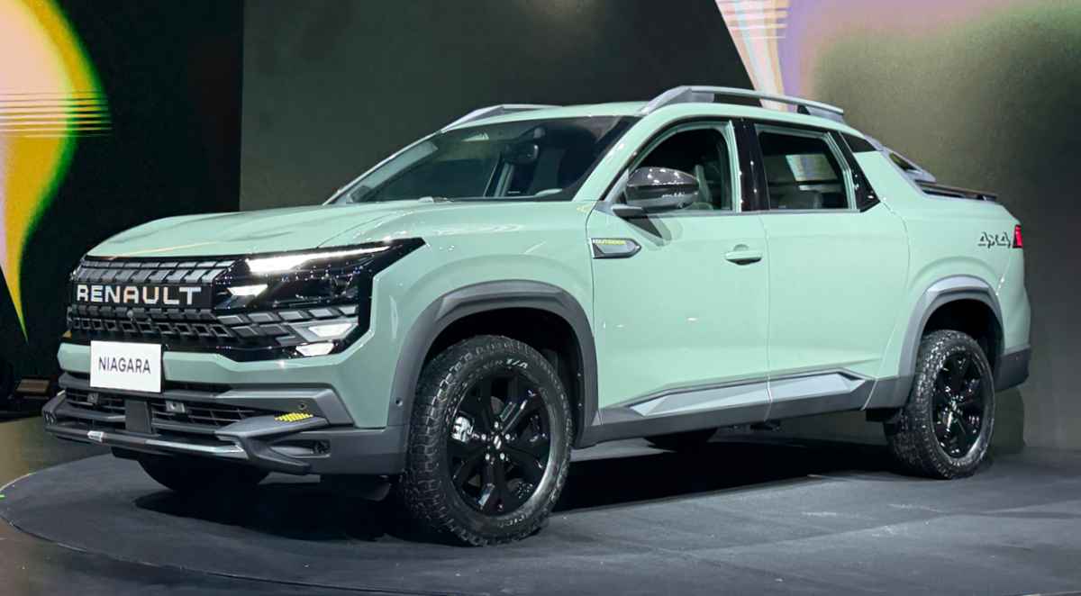 Plano frontal de tres cuartos de la pick-up Renault Niagara color verde claro sobre el escenario de su lanzamiento mundial, exhibiendo su imponente diseño frontal y rines negros.