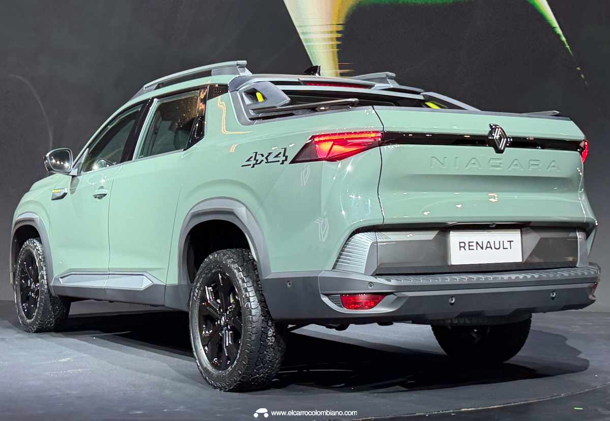 Plano de tres cuartos trasero de la pick-up Renault Niagara color verde claro sobre un escenario oscuro, mostrando el diseño aerodinámico del platón y el emblema 4x4.