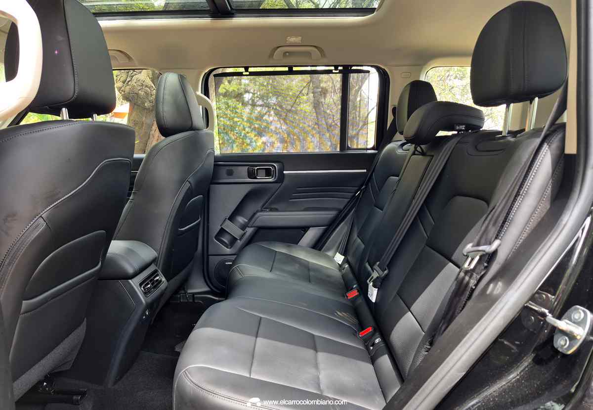 Vista lateral de la segunda fila de asientos de la GWM Haval H7 Full Hybrid, resaltando el espacio para los pasajeros, las salidas de aire acondicionado traseras y las cortinillas en las ventanas.