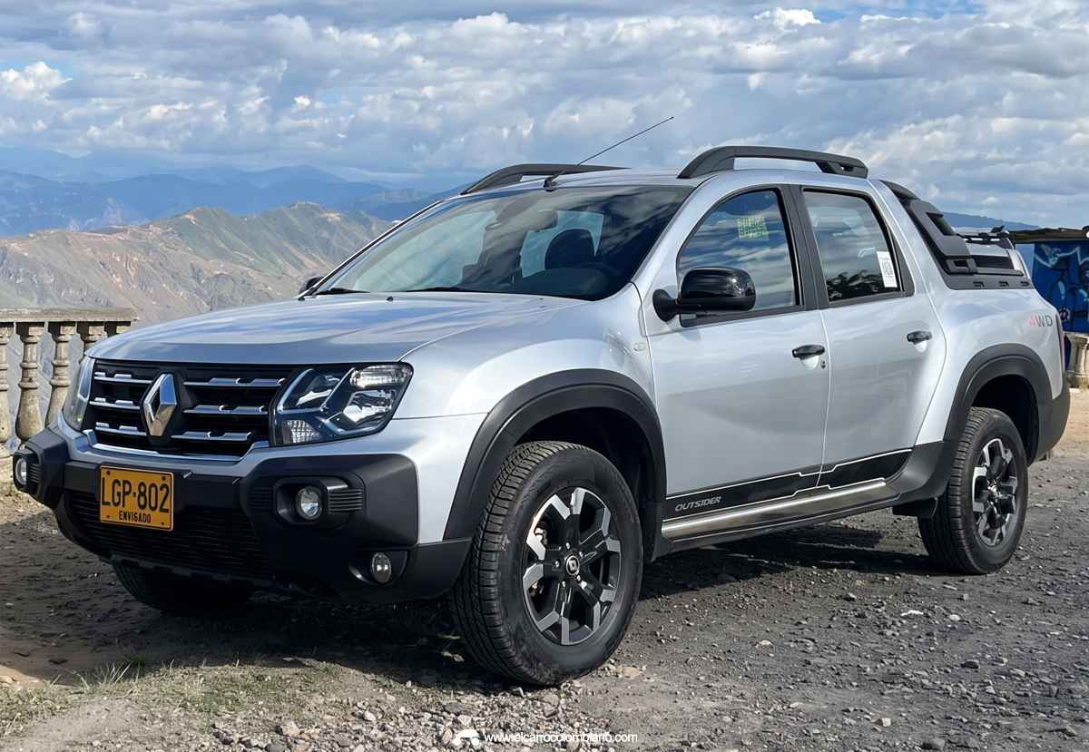 Plano frontal de tres cuartos de la pick-up Renault Oroch Outsider color plata sobre un camino destapado con montañas al fondo, exhibiendo su diseño tradicional y exploradoras.