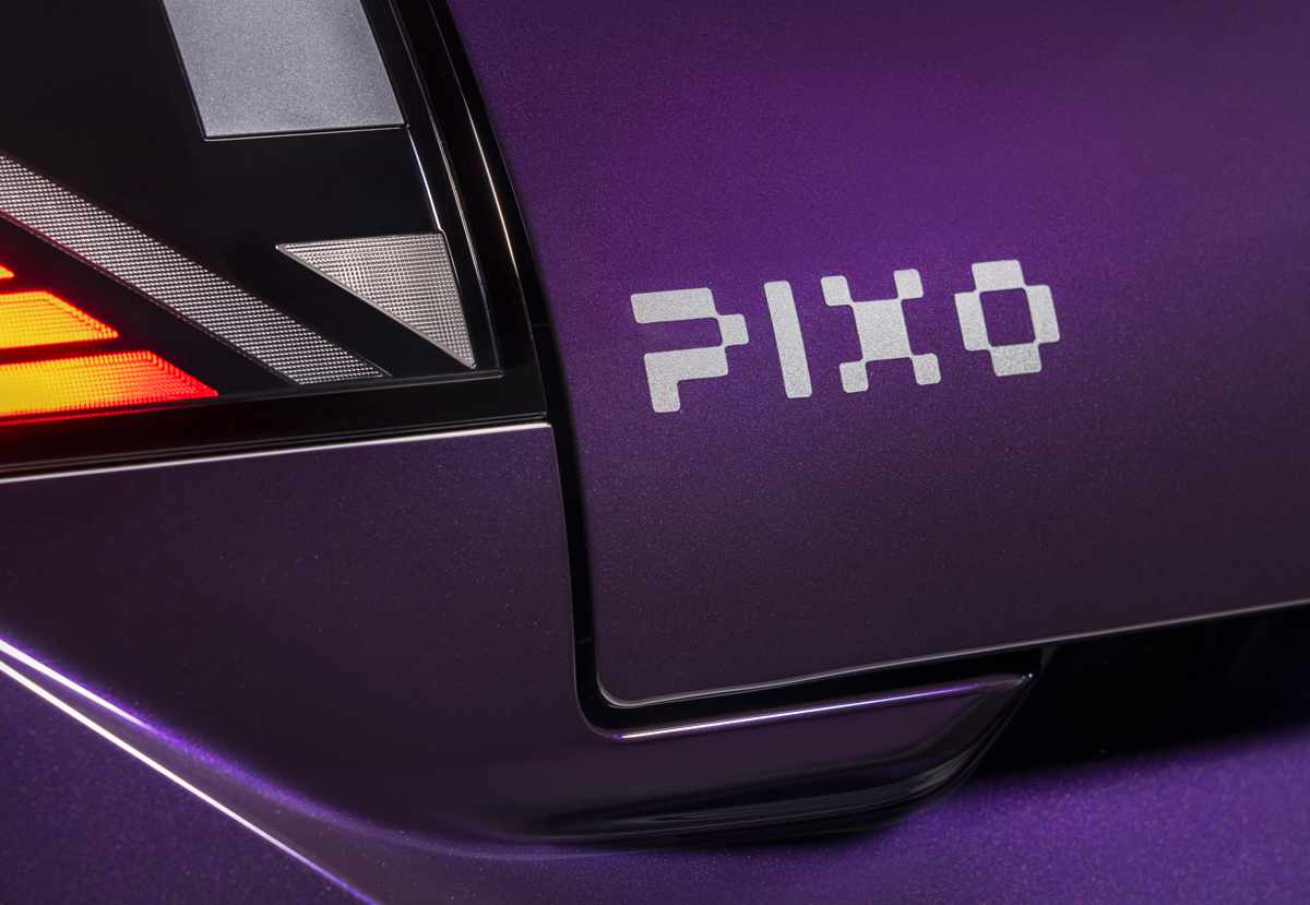 Plano detalle de la compuerta trasera del Nissan Pixo color morado, enfocándose en la original tipografía de estilo píxel utilizada para el nombre del modelo.