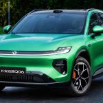 Plano frontal de tres cuartos de la SUV Changan Nevo Q06 verde circulando por una vía rodeada de vegetación, destacando su franja luminosa LED, sensor LiDAR en el techo y rines bitono con mordazas naranjas.