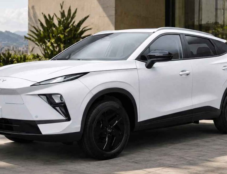 Plano frontal de tres cuartos de la SUV eléctrica Chery E5 blanca estacionada en una plazoleta exterior con palmeras, destacando su frontal cerrado con luces afiladas, rines negros y placa con la denominación E5.