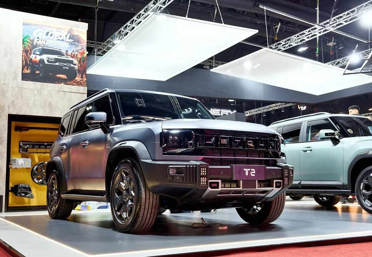 Plano frontal de tres cuartos de la camioneta todoterreno Jetour T2 gris mate en la exposición, ilustrando su diseño cuadrado, parachoques robusto y faros LED de estilo retro.