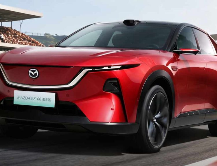 Plano frontal de tres cuartos de la SUV Mazda CX-6e (EZ-60) roja circulando por una pista de carreras, destacando su silueta aerodinámica, luces diurnas afiladas y la parrilla frontal cerrada.