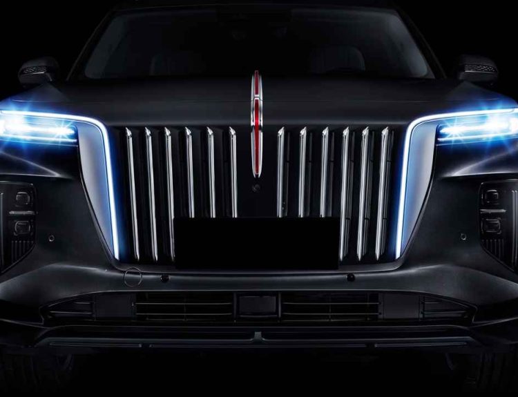 Plano detalle frontal de un vehículo Hongqi E-HS9 sobre fondo oscuro, destacando su imponente parrilla cromada de franjas verticales y la emblemática línea roja iluminada central.
