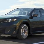 Plano frontal de tres cuartos de la SUV BMW iX3 M60 xDrive verde oscuro en movimiento sobre una carretera, destacando su doble parrilla iluminada y el diseño limpio de la nueva generación Neue Klasse.