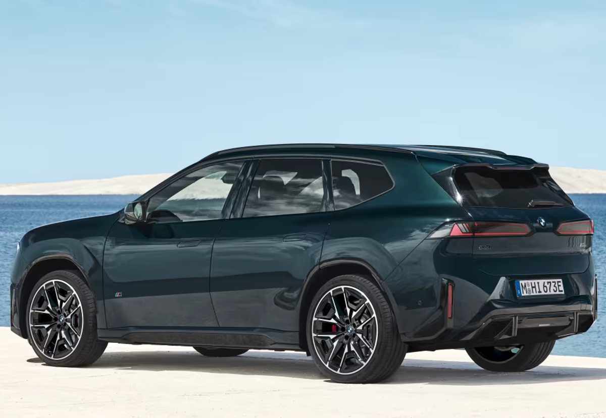 Plano de tres cuartos trasero de la SUV BMW iX3 M60 xDrive verde oscuro, resaltando su difusor inferior aerodinámico negro, las luces posteriores horizontales estilizadas y el alerón integrado en el techo.