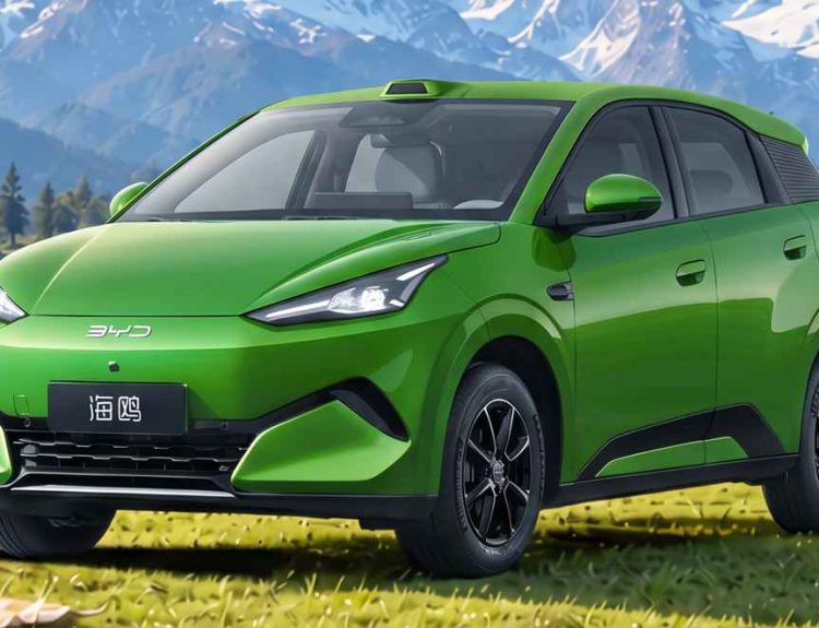 Plano frontal de tres cuartos del nuevo carro eléctrico BYD Seagull color verde estacionado sobre el césped frente a un lago y montañas nevadas, destacando su carrocería más larga, sensor LiDAR en el techo y rines negros de 16 pulgadas.