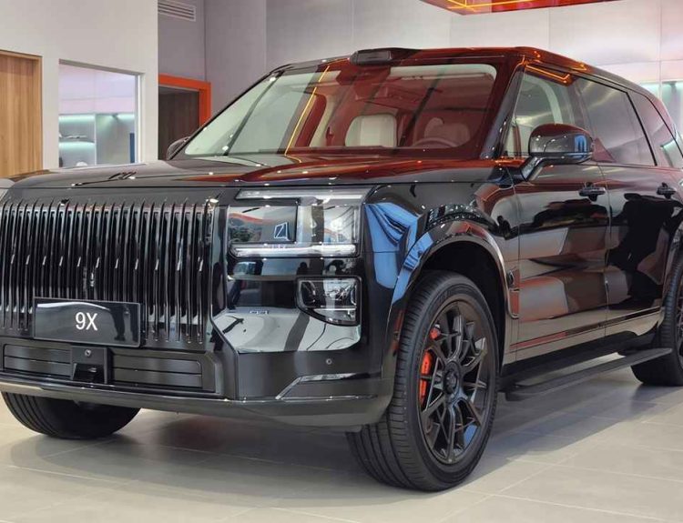 Plano frontal de tres cuartos de la lujosa SUV híbrida Zeekr 9X color Negro Onyx en vitrina de Colombia, destacando su imponente parrilla vertical, sensor LiDAR en el techo y rines negros de 22 pulgadas con pinzas naranjas.